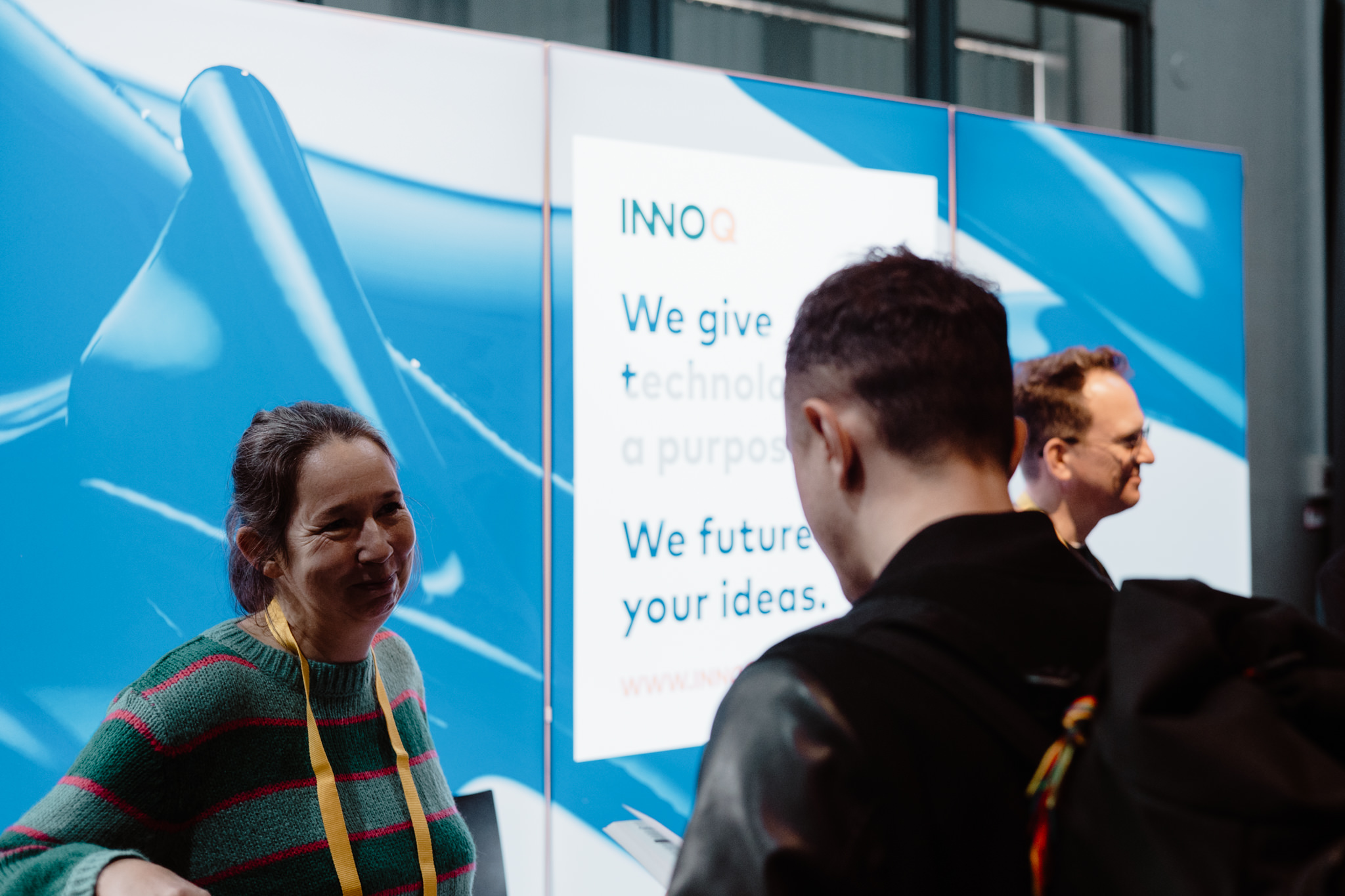 Two attendees chatting at the sponsor wall